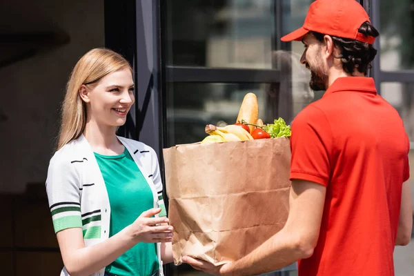 Courier Segurando Saco Papel Com Supermercado Perto Mulher Sorridente Rua — Fotografia de Stock