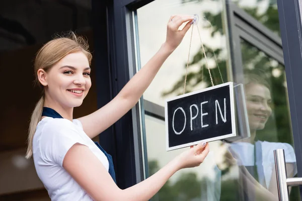 Vista Lateral Garçonete Sorrindo Para Câmera Enquanto Pendura Tabuleta Com — Fotografia de Stock