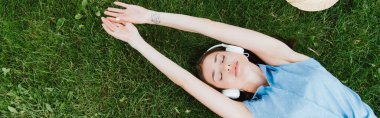 Çimlere uzanıp müzik dinleyen çekici bir kadının panoramik mahsulü.