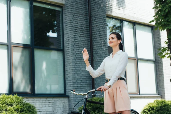 Cheerful Young Businesswoman Standing Bike Waving Hand — Stock Photo, Image