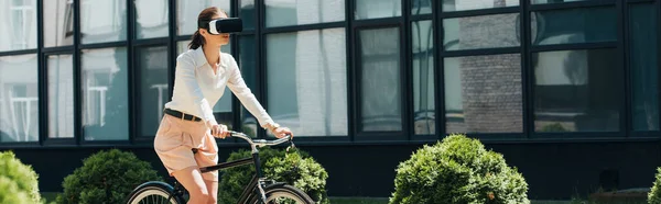 ビルの近くの自転車に乗るバーチャルリアリティのヘッドセットのビジネス女性のパノラマの概念 — ストック写真