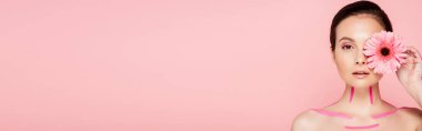 Vücudunda pembe çizgiler ve gözünün yanında kasımpatı olan çıplak, güzel bir kadın. Pembe panoramik bir karede izole edilmiş.