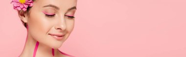 Pembe çizgileri olan güzel bir kadın ve pembe, panoramik bir karede izole edilmiş bir çiçek.
