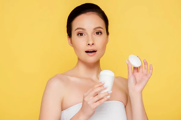 shocked beautiful woman holding stick deodorant isolated on yellow