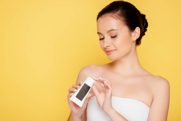 beautiful brunette woman holding hand cream isolated on yellow