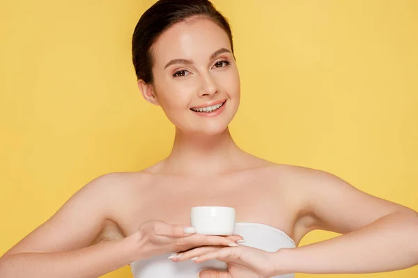 Sonriente Hermosa Mujer Sosteniendo Contenedor Con Crema Cosmética Aislado Amarillo — Foto de Stock