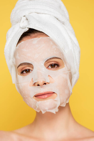 naked beautiful woman with towel on head and face mask isolated on yellow
