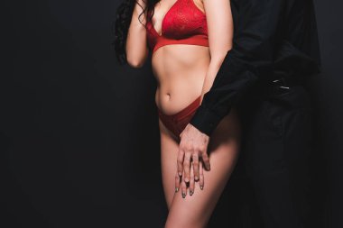Kırmızılı, siyah iç çamaşırlı, ateşli bir adamın seksi kız arkadaşına dokunuşunun görüntüsü.