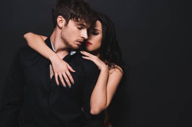 seductive woman hugging boyfriend isolated on black 