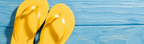 top view of yellow flip flops on wooden blue background, panoramic shot