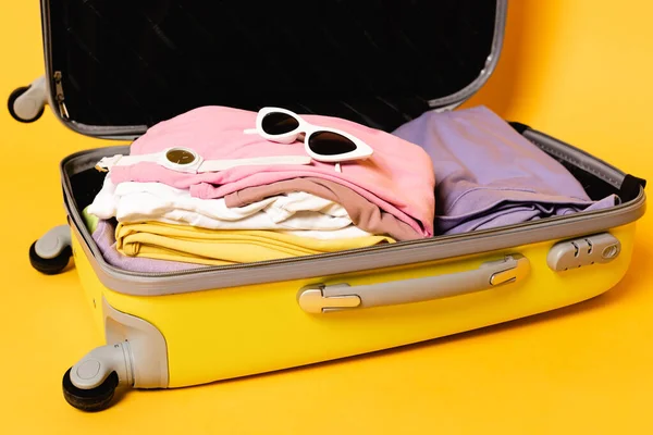 Ανοιχτή Τσάντα Ταξιδιού Καλοκαιρινά Ρούχα Και Αξεσουάρ Κίτρινο Φόντο — Φωτογραφία Αρχείου