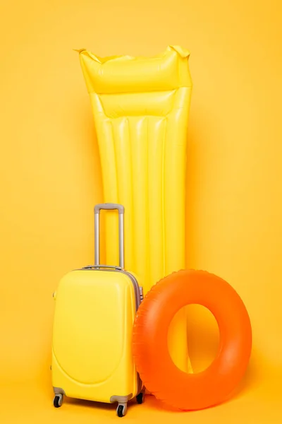 黄色背景上装有游泳池浮子的旅行袋 — 图库照片
