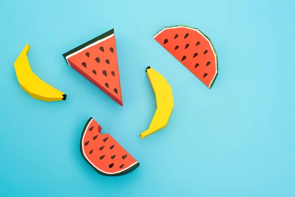 top view of paper watermelon and bananas on blue background