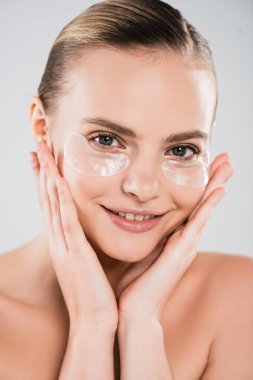 Göz bantlı neşeli bir kız Gri üzerinde izole edilmiş yüzlere dokunuyor