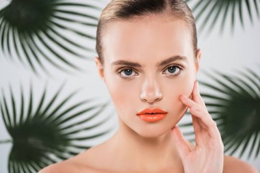 Çekici bir kadın kameraya bakıyor ve beyaz bir yüze dokunuyor.