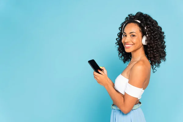 Alegre Chica Afroamericana Escuchando Música Auriculares Inalámbricos Sosteniendo Teléfono Inteligente — Foto de Stock