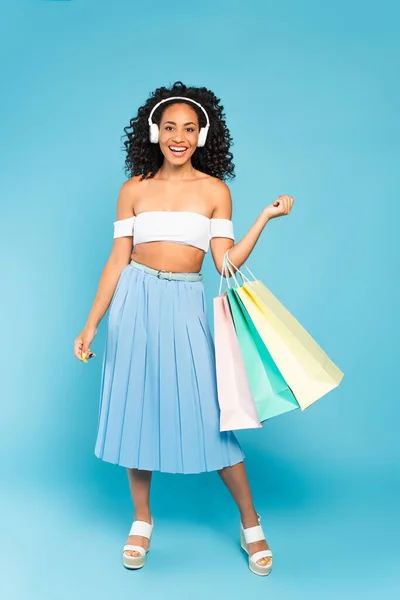 Chica Afroamericana Feliz Sosteniendo Bolsas Compras Escuchando Música Auriculares Azul — Foto de Stock