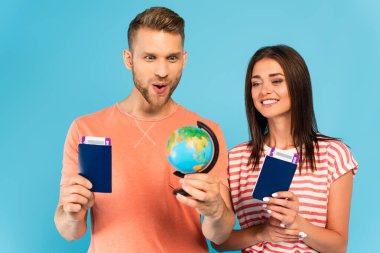 Mutlu çift, pasaportlarını mavi renkte tutarken dünyaya bakıyor.