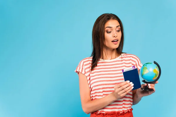 Zaskoczona Dziewczyna Posiadające Paszport Patrząc Globus Odizolowany Niebiesko — Zdjęcie stockowe