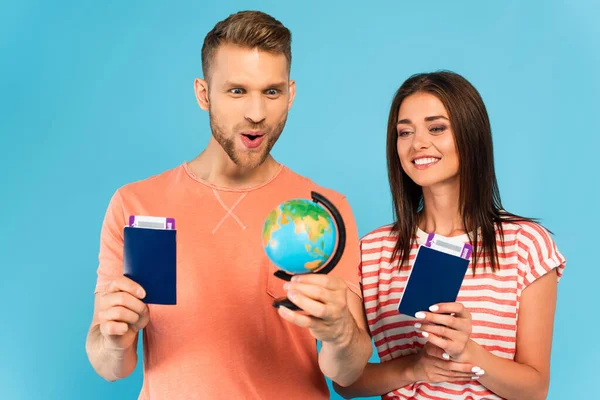 Casal Feliz Olhando Para Globo Enquanto Segurando Passaportes Isolados Azul — Fotografia de Stock