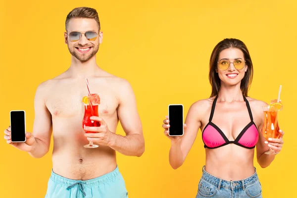 スマートフォンを持っている幸せなカップルと黄色に隔離されたスクリーンとカクテル — ストック写真