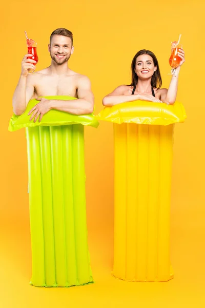 Happy Couple Looking Camera Holding Cocktails Inflatable Mattresses Yellow — Stock Photo, Image