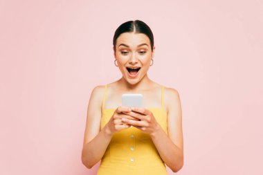 Pembe üzerine izole edilmiş akıllı telefon kullanan esmer bir kadın.
