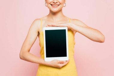 Kırpılmış pembe ekranlı dijital tablet tutan genç kadın görüntüsü
