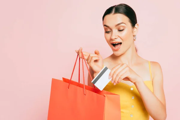 Excitada Morena Joven Poniendo Tarjeta Crédito Bolsa Aislada Rosa — Foto de Stock