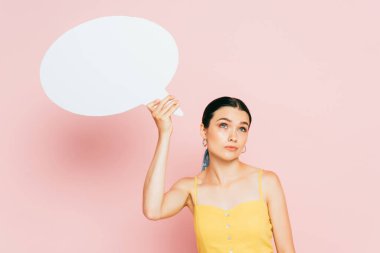 Pembe üzerine beyaz boş konuşma balonu olan düşünceli esmer genç kadın.