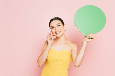 Yeşil, boş konuşma baloncuğu olan esmer genç bir kadın akıllı telefondan pembe üzerine konuşuyor.