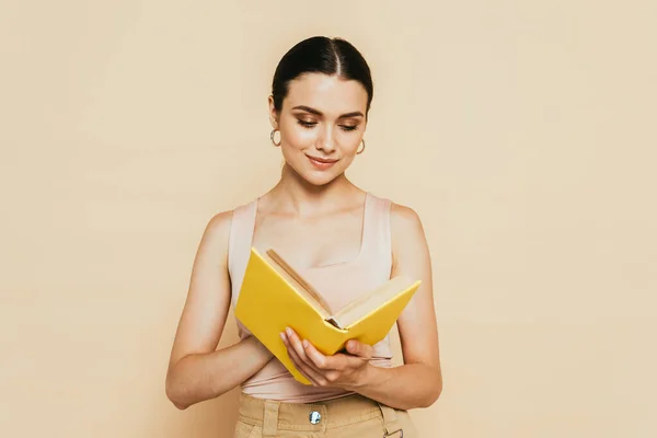 Jovem Morena Lendo Livro Amarelo Isolado Bege — Fotografia de Stock