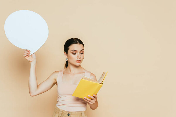 brunette young woman with blank speech bubble reading book on beige