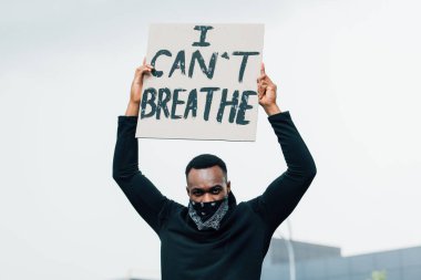 Afro-Amerikan adam kameraya bakıyor ve levha tutuyor. Dışarıda harflerle nefes alamıyorum. 
