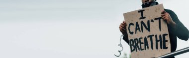 panoramic crop of handcuffed african american man holding placard with i cant breathe lettering outside  clipart