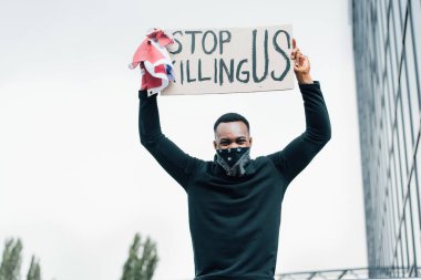 african american man holding flag of america and placard with stop killing us lettering outside  clipart