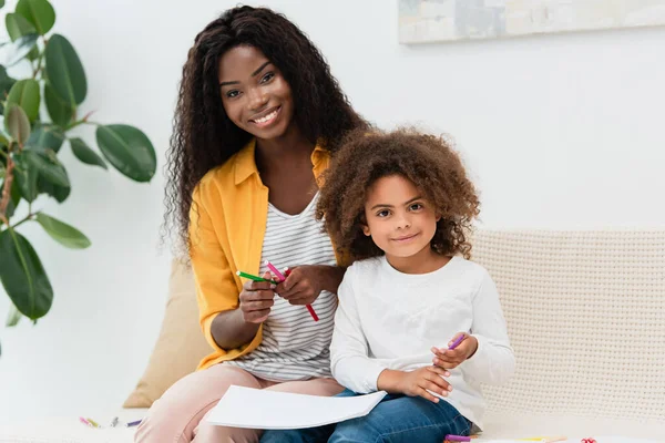 Madre Afroamericana Hija Sosteniendo Lápiz Color Mientras Están Sentadas Sofá — Foto de Stock