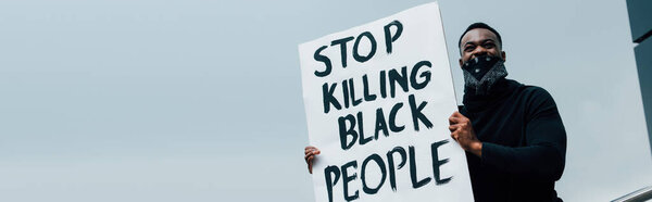panoramic concept of african american man holding placard with stop killing black people lettering outside 