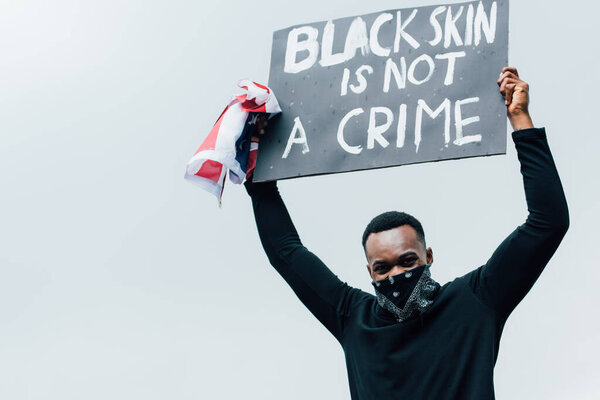 african american man holding flag of america and placard with black skin is not a crime lettering outside