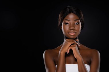 Çenesinin altında elleri olan Afro-Amerikalı bir kadın, siyahta izole edilmiş kameraya bakıyor.