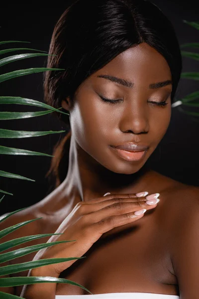 非洲裔美国裸体女人 紧闭双眼 靠近绿色棕榈叶 与黑色隔离 — 图库照片