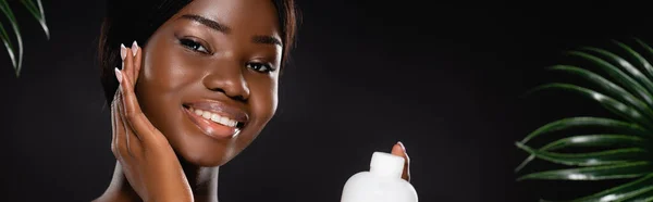 Афроамериканська Жінка Тримає Пляшку Лосьйону Біля Зеленого Листя Долоні Ізольовано — стокове фото