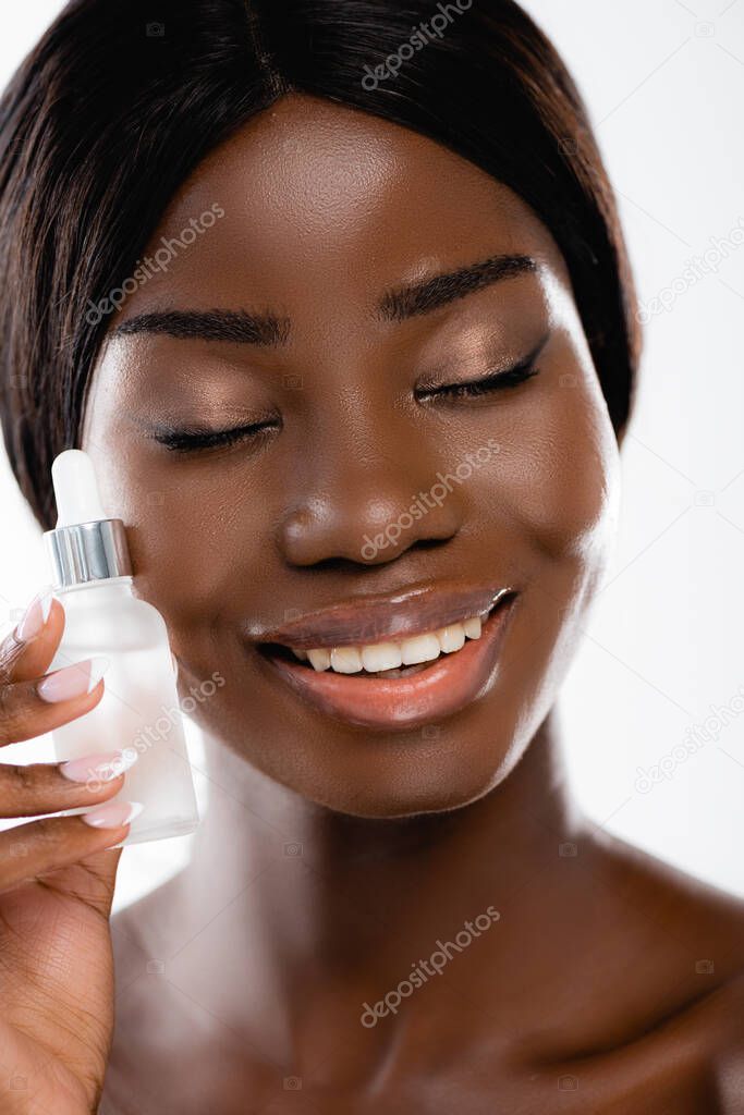 naked african american woman with closed eyes holding bottle of serum isolated on white