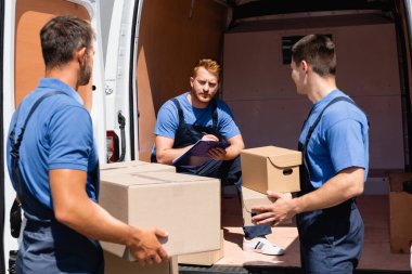 Karton paketleri açık havada tutan meslektaşlarının yanında panoya yükleyici yazısının seçici odak noktası