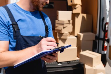 Arka planda paketli kalem ve pano taşıyan yükleyicinin kırpılmış görünümü