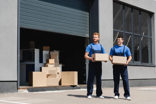 Movers Overalls Holding Cardboard Boxes Looking Away Urban Street — Stock Photo, Image