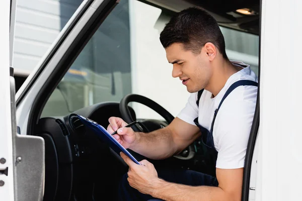 Selective Focus Concentrated Loader Writing Clipboard While Sitting Driver Seat — Stock Photo, Image