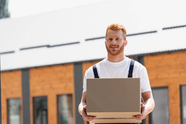 Loader holding cardboard box on urban street 