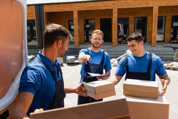 Selective Focus Loader Clipboard Pointing Finger Colleagues While Unloading Cardboard — Stock Photo, Image