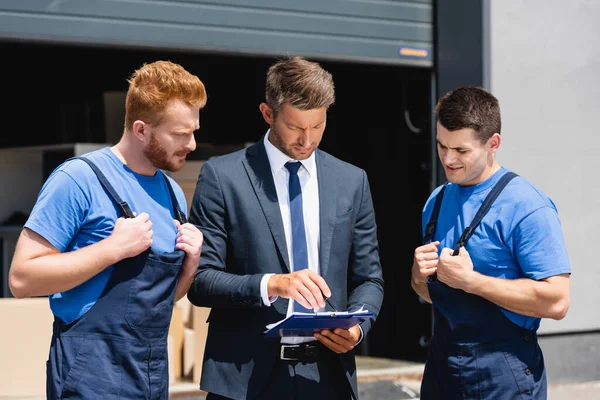 Affärsman Hålla Penna Och Urklipp Nära Lastare Utomhus — Stockfoto